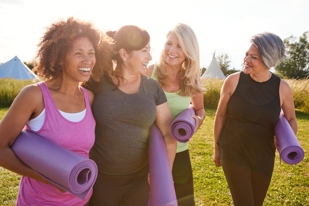 Group of mature female friends on outdoor Yoga Retreat walking