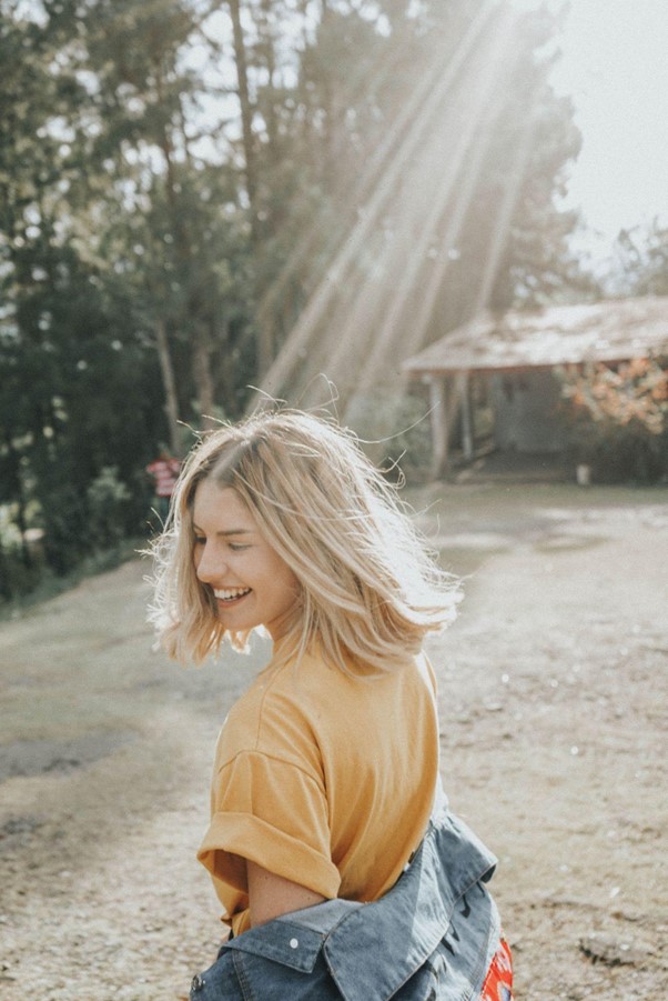 Woman with blonde hair in the countryside enjoying the open air and sun rays.